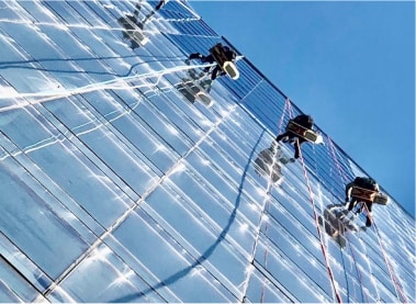Three Top Team employees are rappelling down the facade of the skyscraper on ropes