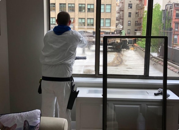 An employee of Top Team is cleaning a window with chemicals 